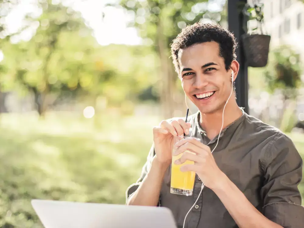 young man drinking orange juice and smiling