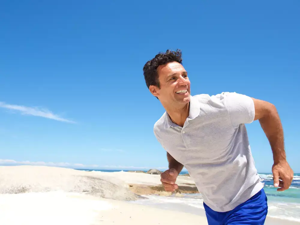 Portrait of a cheerful middle aged man running on the beach